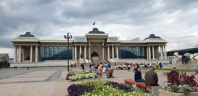 Parliament building in Ulaanbaatar, Mongolia with people sitting and walking outside.