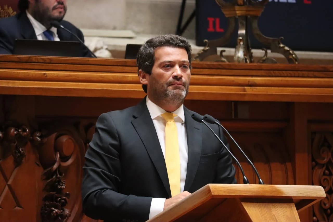 André Ventura, President of Chega, stands at a wooden podium speaking into microphones.