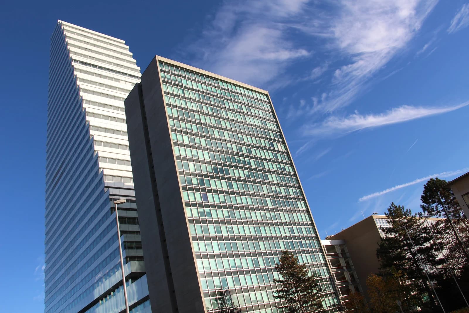 Modern high-rise office buildings under a bright blue sky in Basel, Switzerland.