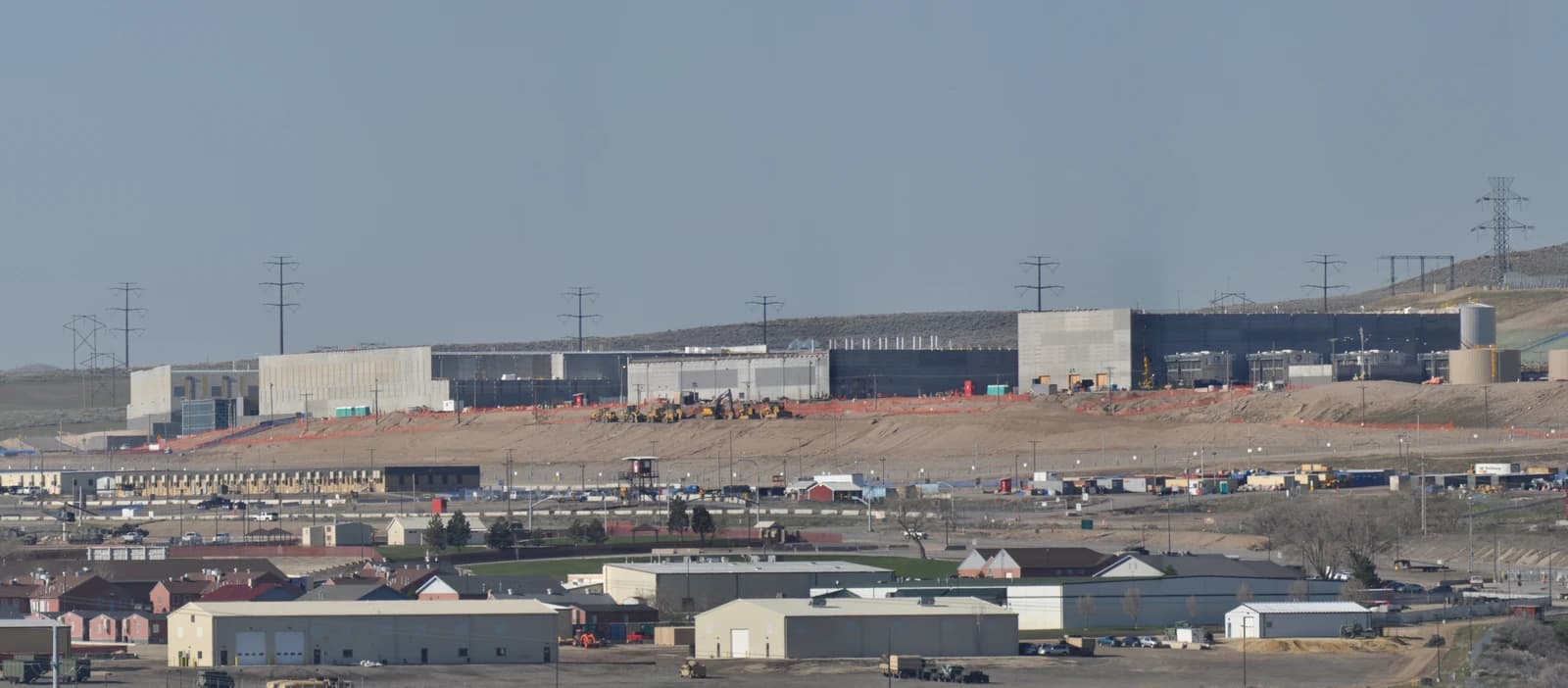 Panorama of large data center buildings under construction in a desert landscape.