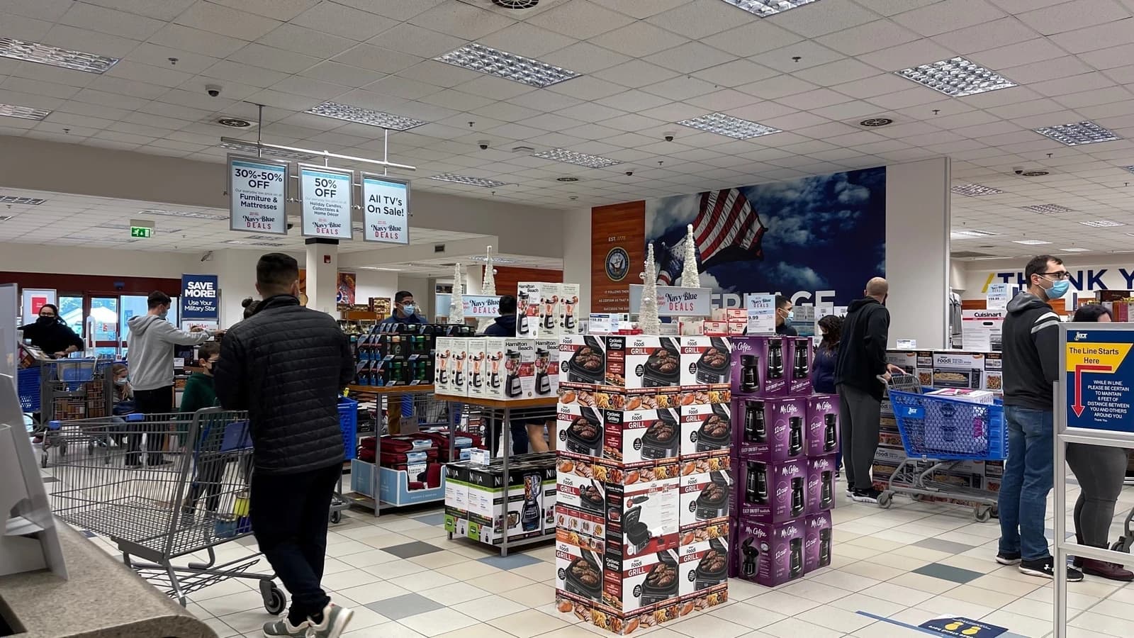Shoppers in face masks browse sale items at NEX Navy Exchange retail store.