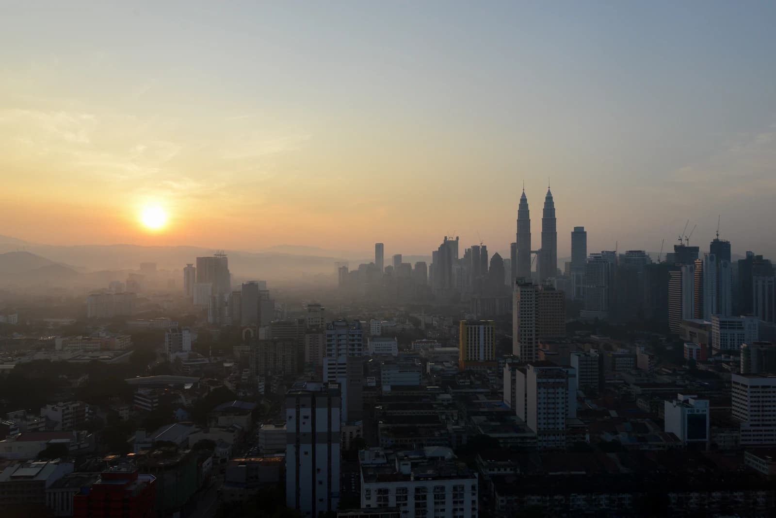 Kuala Lumpur skyline at sunrise with the Petronas Towers prominent amidst other buildings.