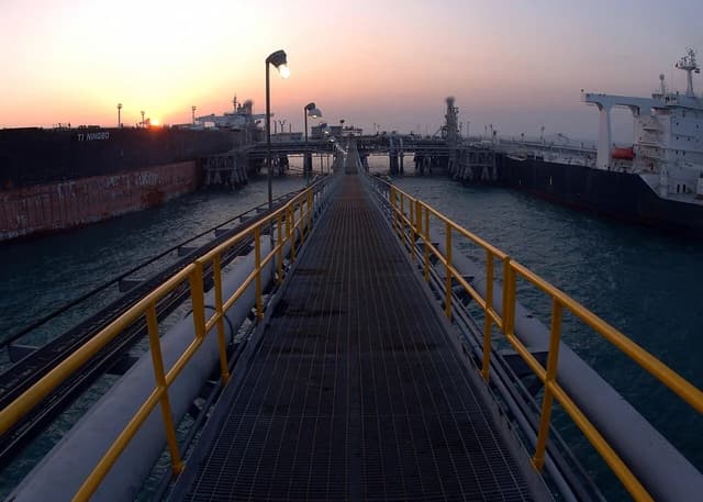Sunrise over the Al Basra Oil Terminal with large oil tankers docked for loading.