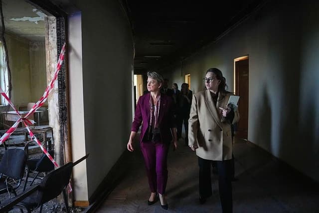 Foreign Secretary Yvette Cooper and another woman walking through a damaged building in Kyiv.