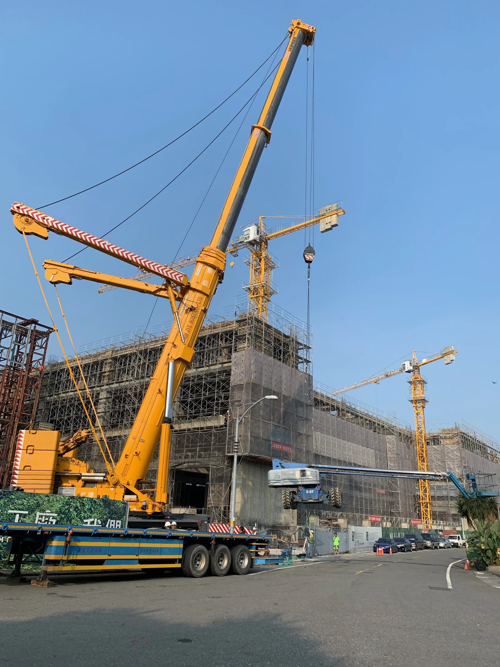 Large yellow Liebherr LTM 1500-8.1 crane truck alongside a building under construction.