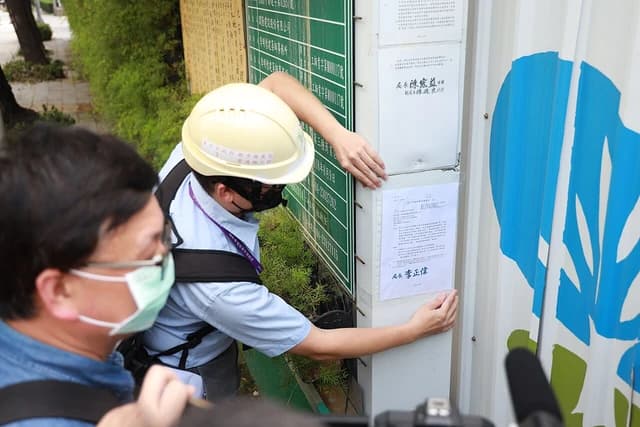 Construction worker in a hard hat posting official documents at a building construction site.