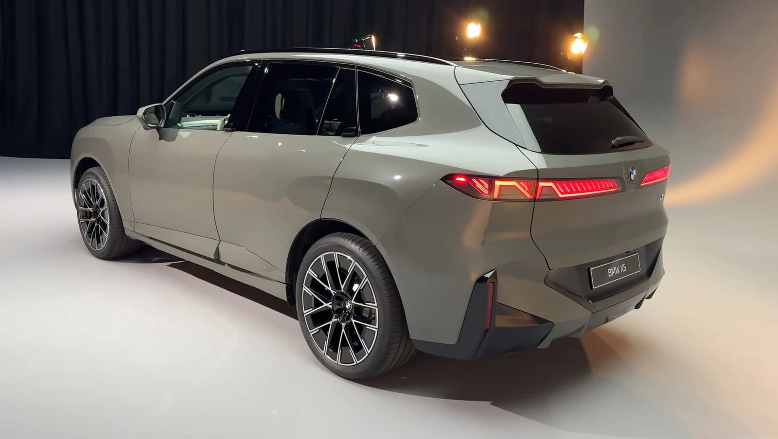 Rear left view of a grey BMW iX5 (G65) SUV on a showroom floor.
