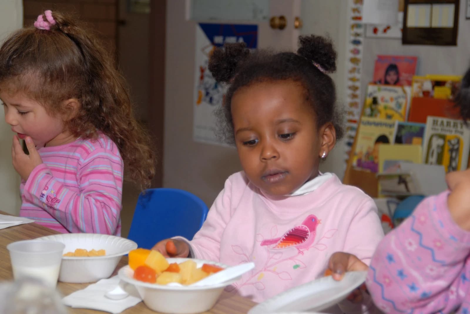 Children eating meals at a table in a daycare setting.
