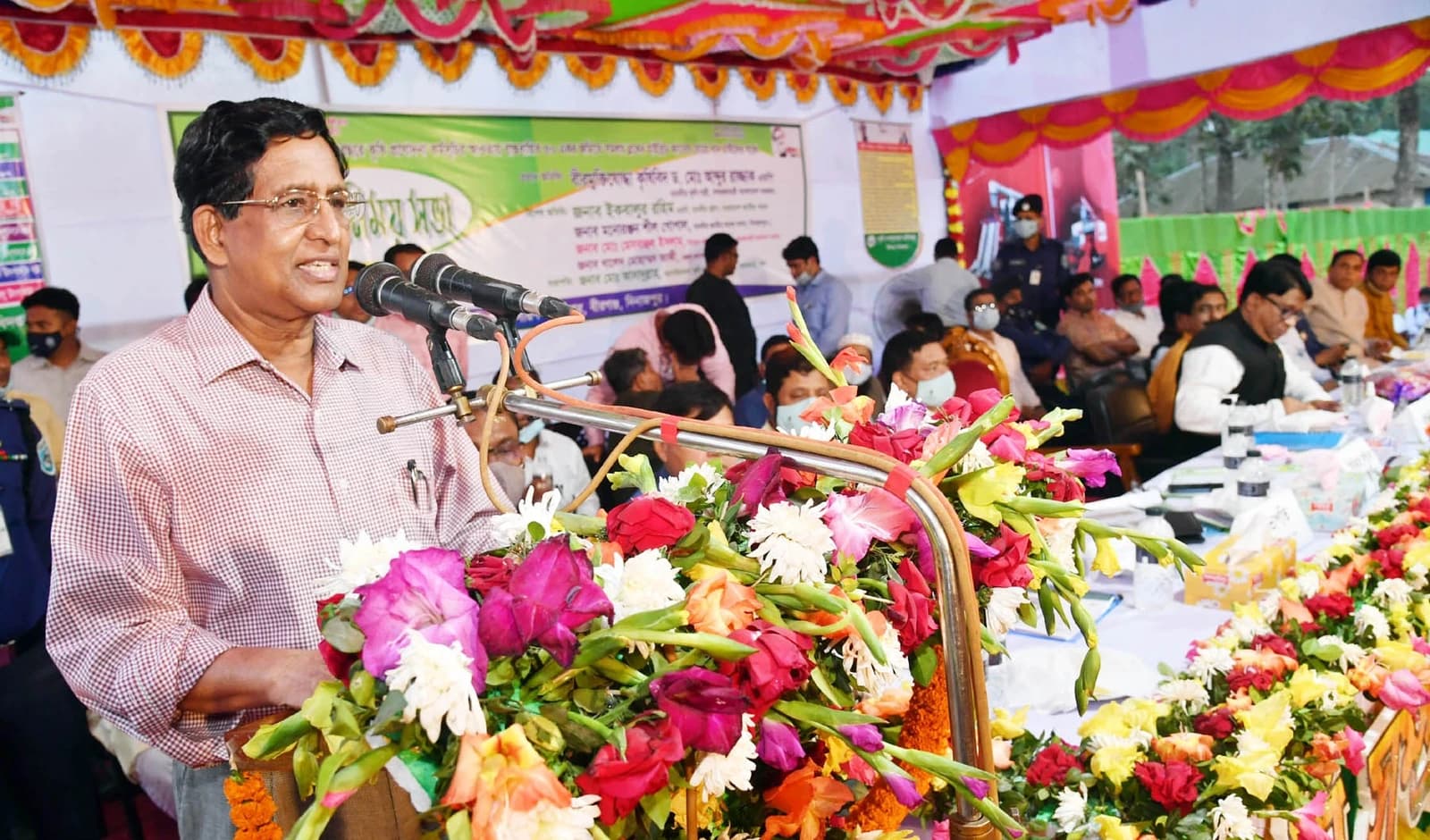 Agriculture Minister speaking from a podium decorated with flowers.