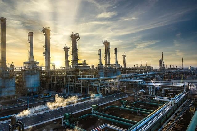 An expansive view of the ADNOC Refining Ruwais site with various refinery components at sunset.