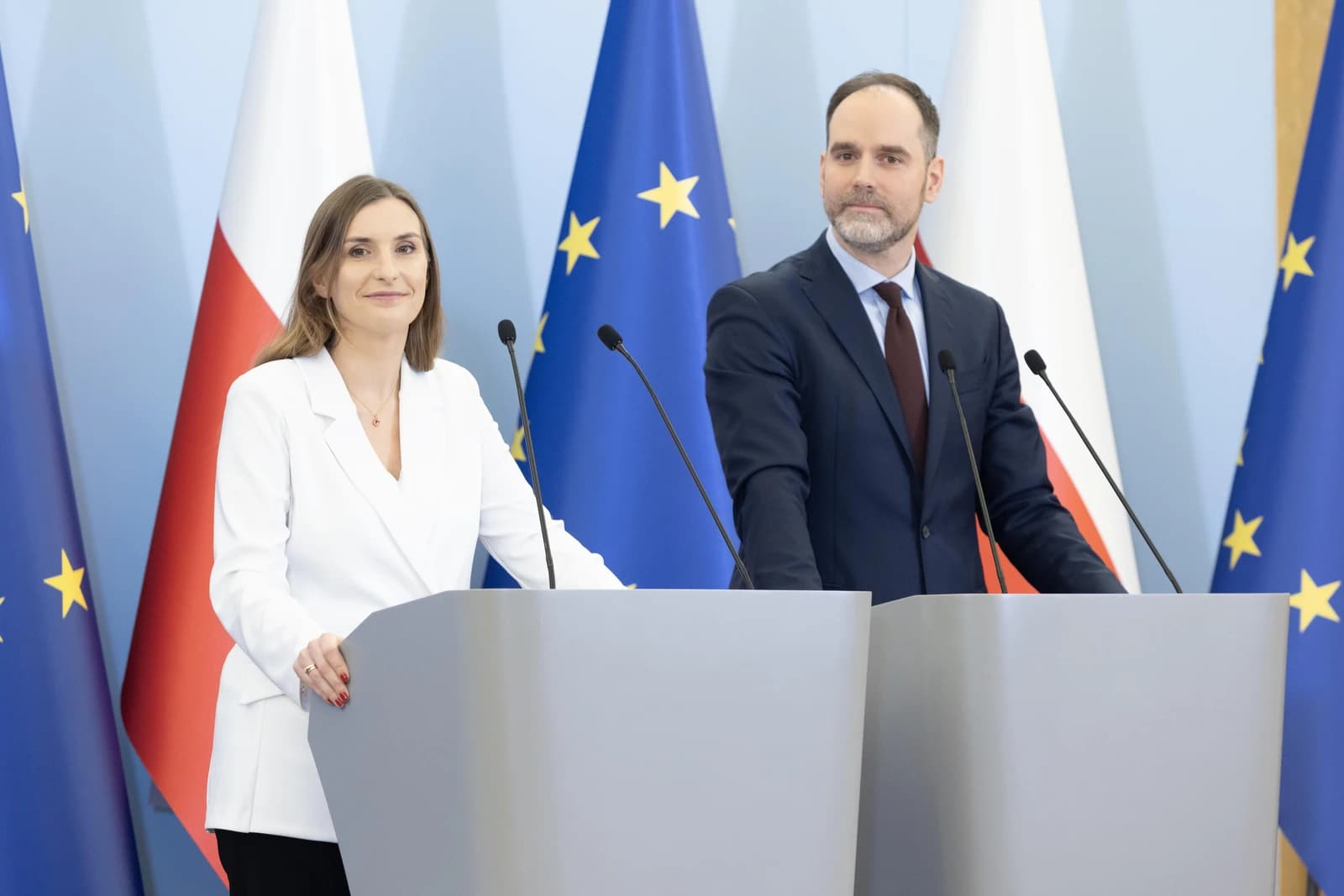 Man and woman standing at podiums during a press conference.
