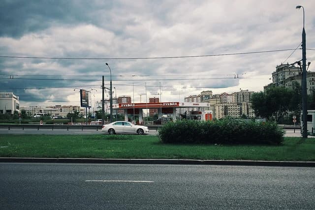 Lukoil gas station building in Moscow on a cloudy day, with a car passing by.