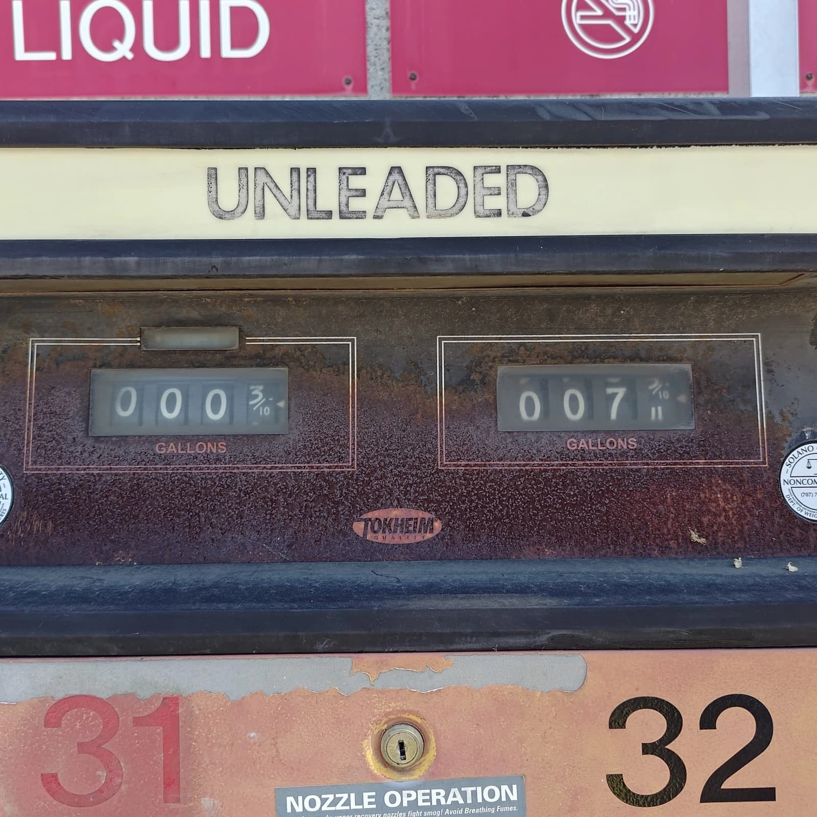 Close-up view of an old gasoline pump showing 'UNLEADED' and gallon counters.
