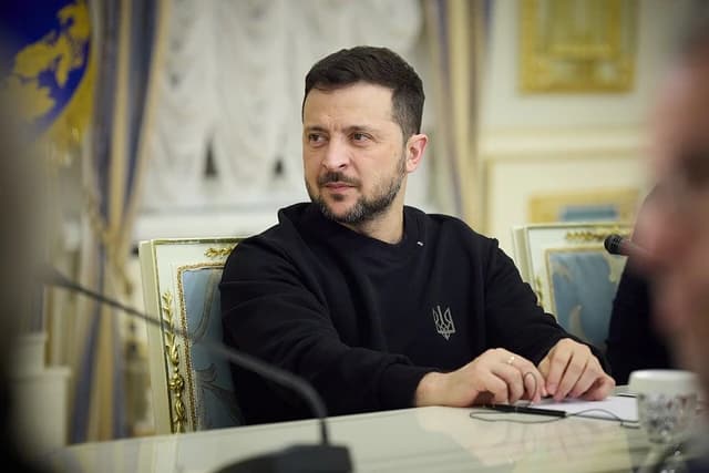 Volodymyr Zelenskyy, President of Ukraine, seated at a table during a meeting.