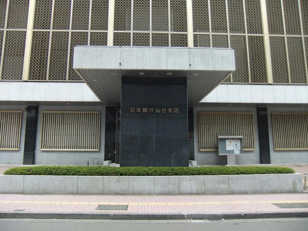 Exterior of the Bank of Japan Sendai Branch building with Japanese text above the entrance.
