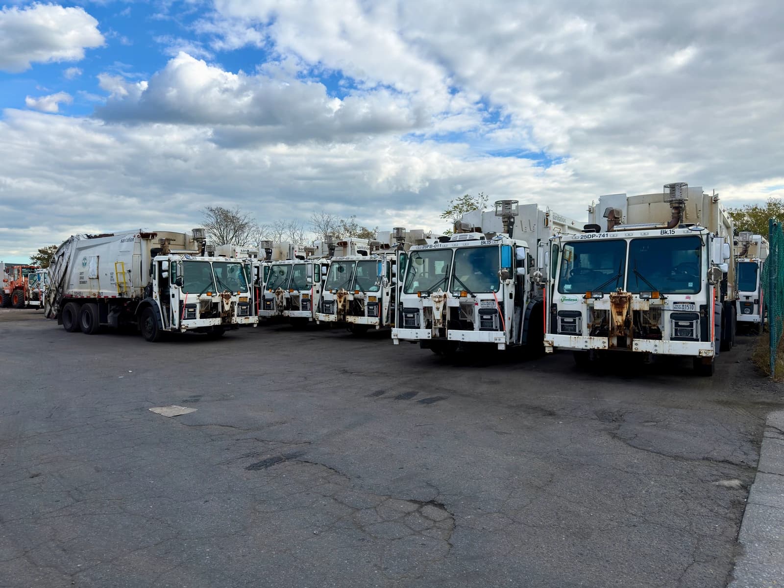 New York City Department of Sanitation garbage trucks parked in a lot.