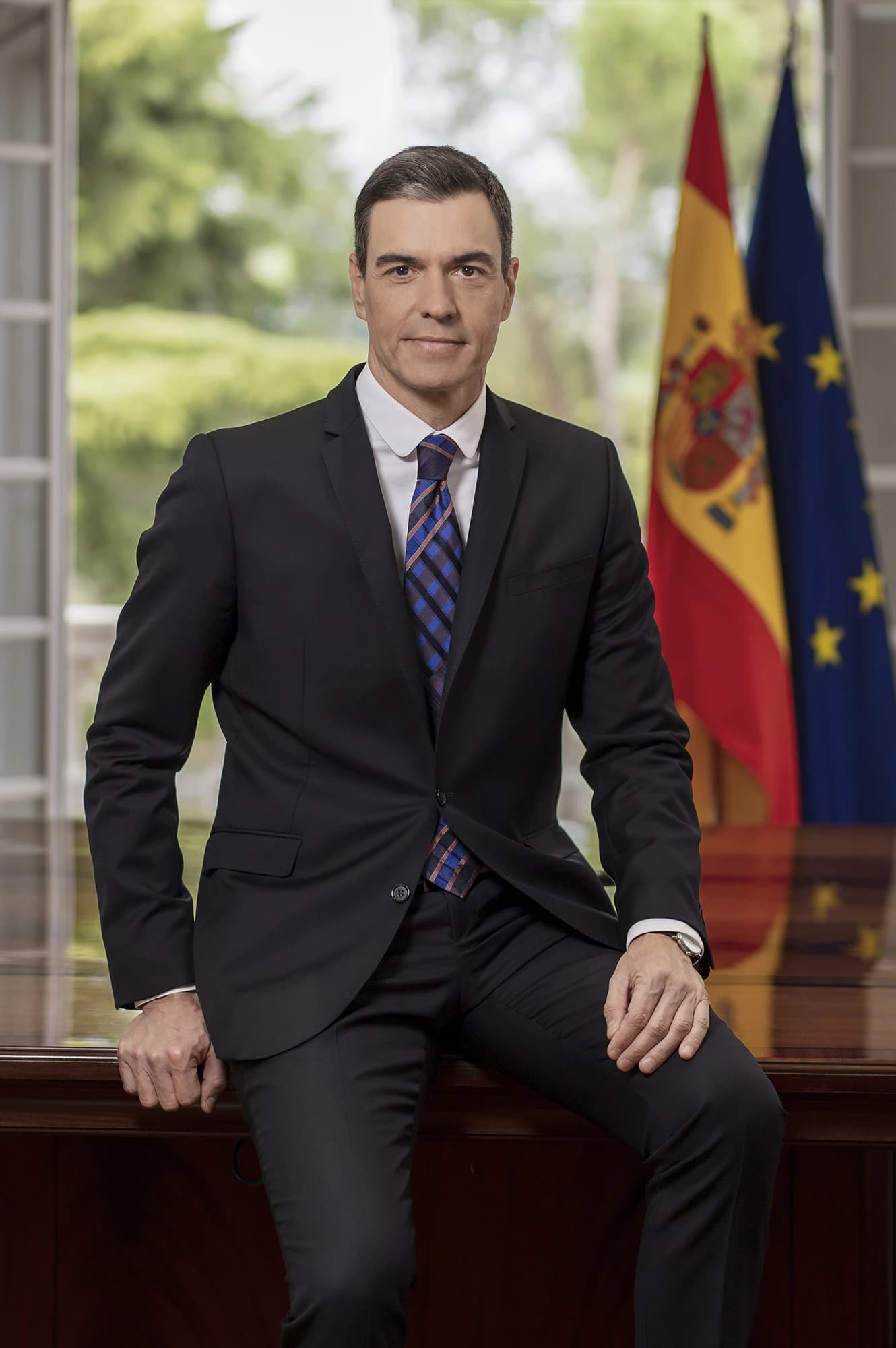Pedro Sánchez, President of the Government of Spain, seated on a desk.