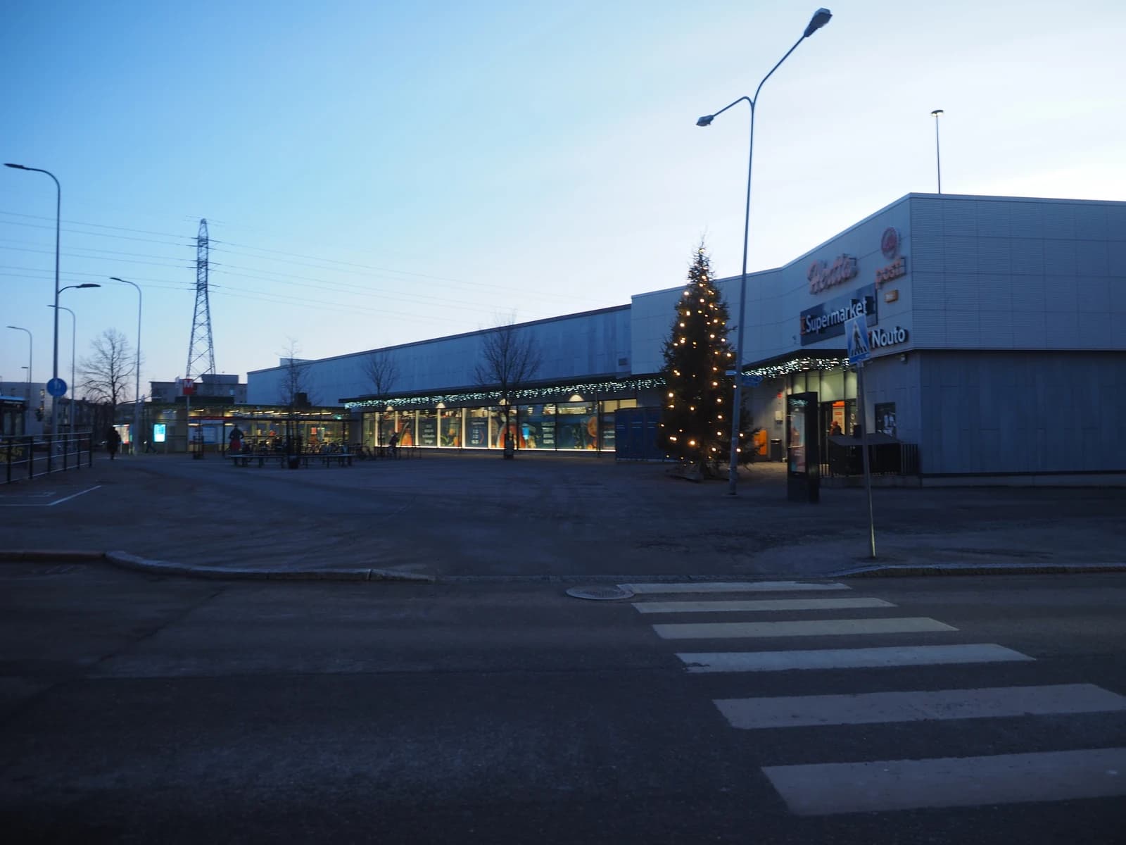Exterior view of K-Supermarket Hertta building with a decorated Christmas tree outside.