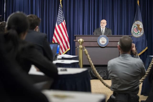 Ben Bernanke, Chairman of the Federal Reserve, speaking at a podium during a press conference.