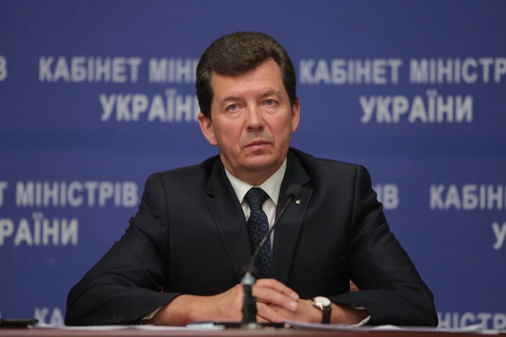 Man in a suit and tie speaking at a press conference.