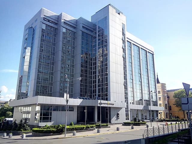 Modern building with glass facade, Ukrainian Railway headquarters, on a sunny day.
