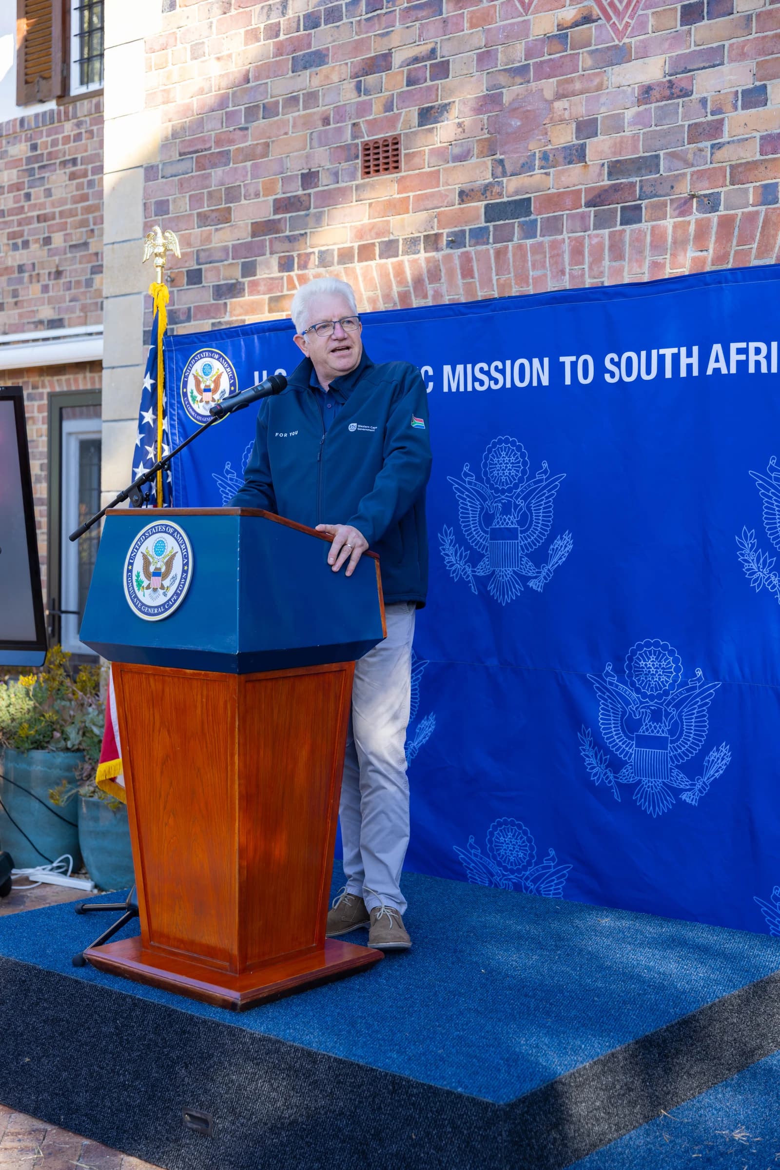 Western Cape Premier Alan Winde speaks at a podium outdoors.