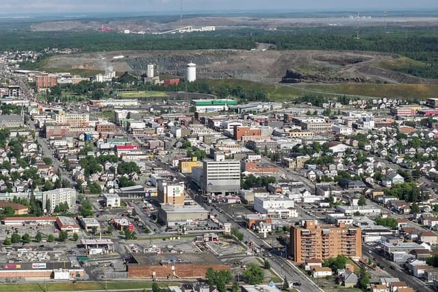 Aerial view of Timmins, Ontario, with a city foreground and mining infrastructure beyond.