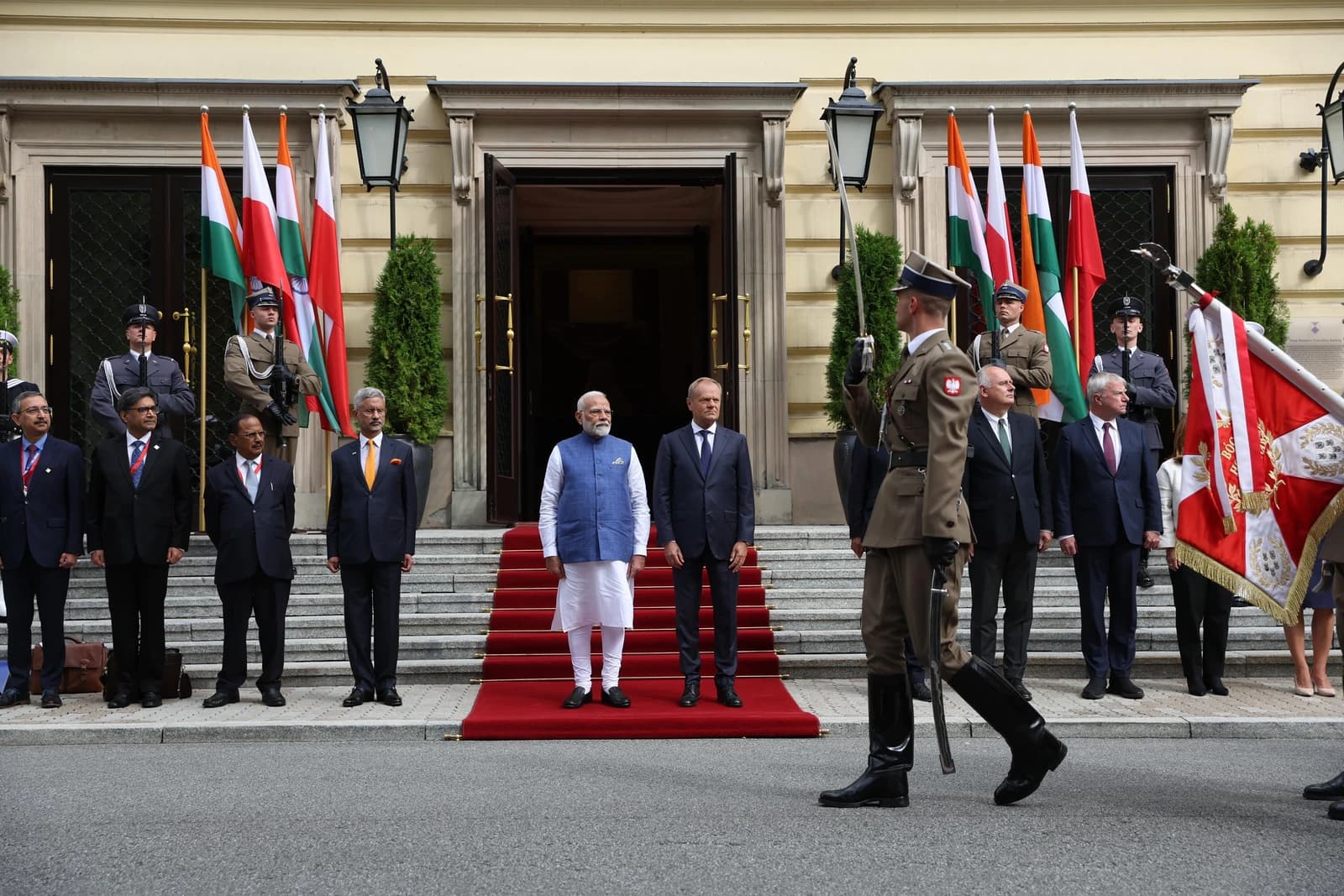 Narendra Modi, Prime Minister of India, and Donald Tusk, President of the European Council, stand outdoors with officials.