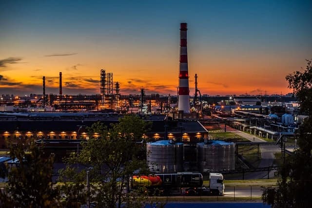 Moscow oil refinery illuminated at dusk, with industrial structures and a tanker truck.