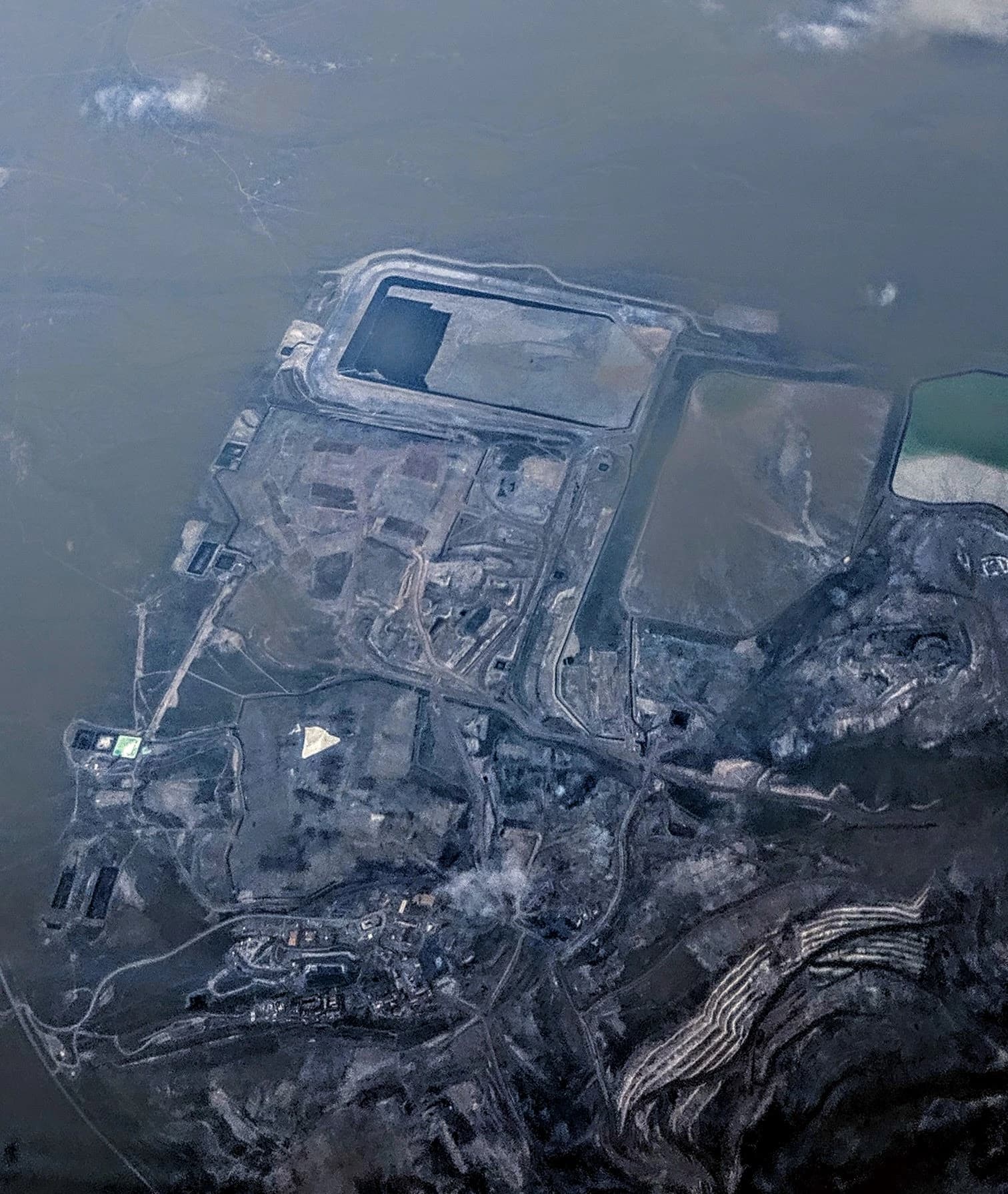 Aerial view of an extensive open-pit gold mining operation with infrastructure and settling ponds.