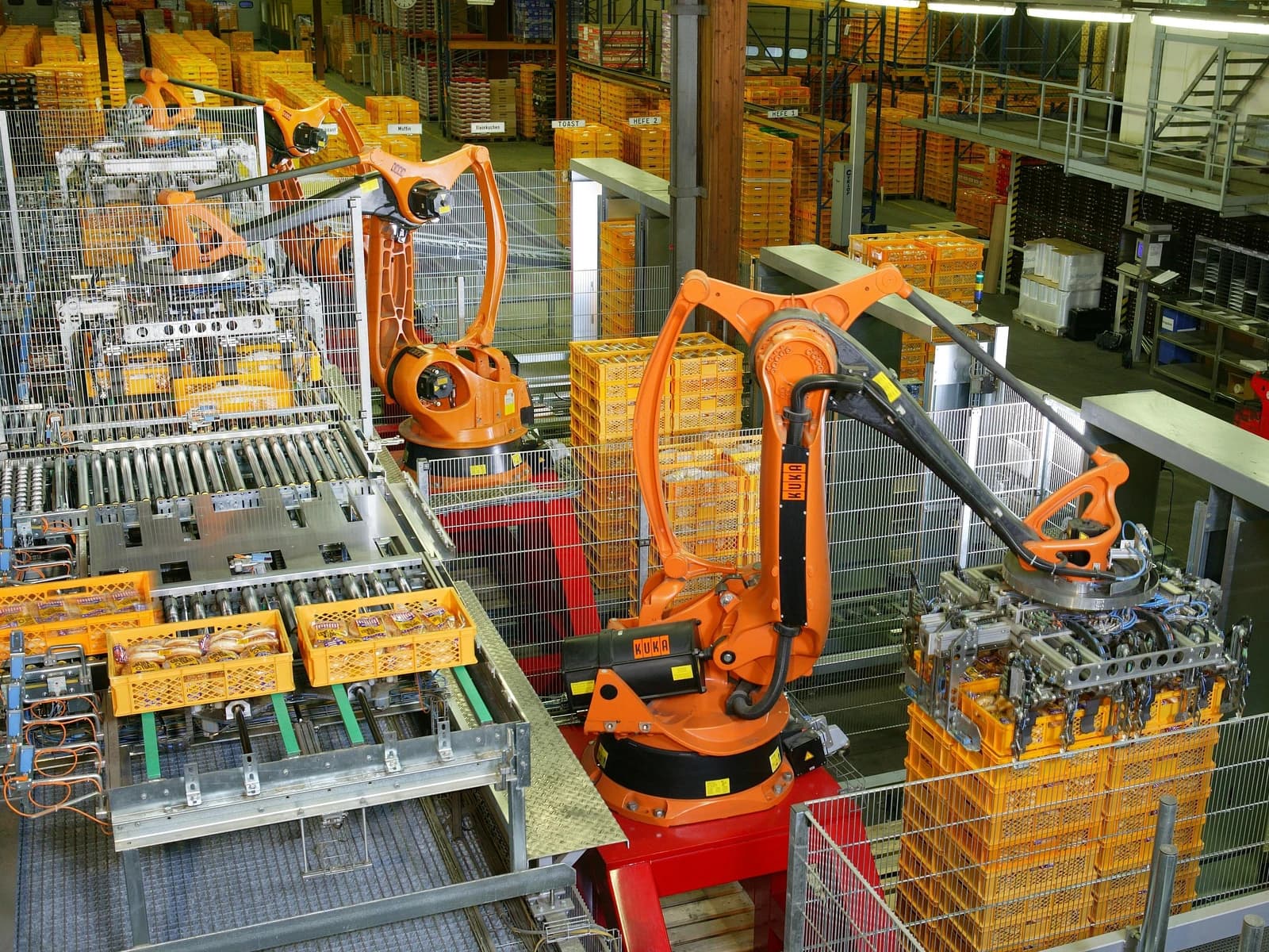 Robotic arms automatically packaging bread products and stacking them onto pallets in a factory.
