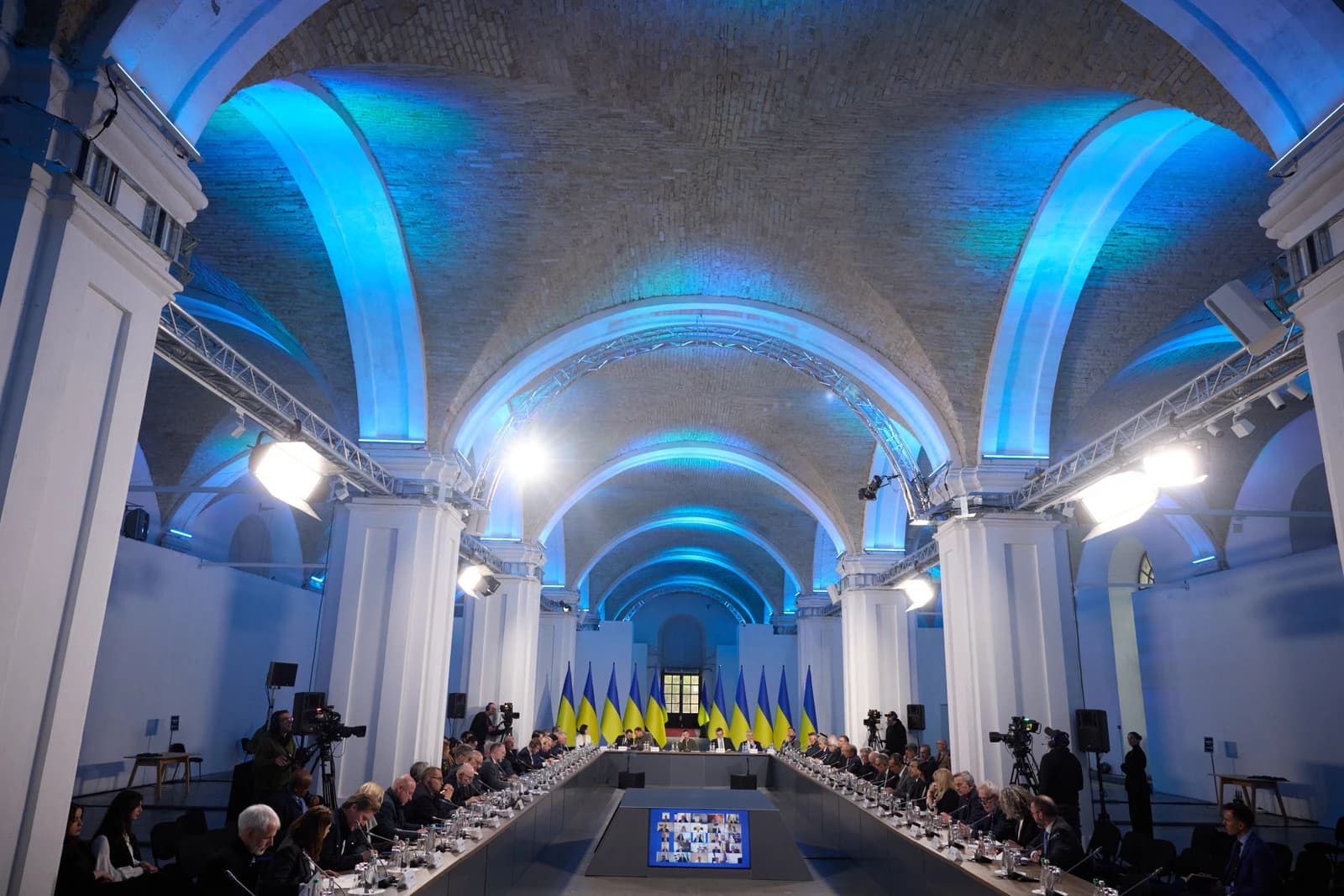 Volodymyr Zelenskyy seated at the head of a long table, surrounded by ambassadors.