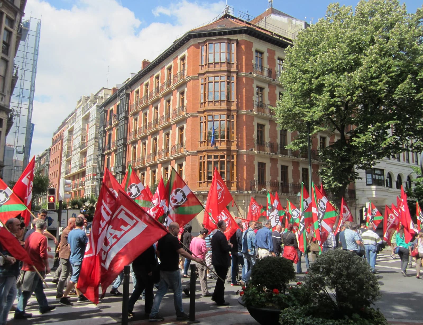 Protestors carrying flags of CCOO, LAB, and UGT unions in Bilbao.