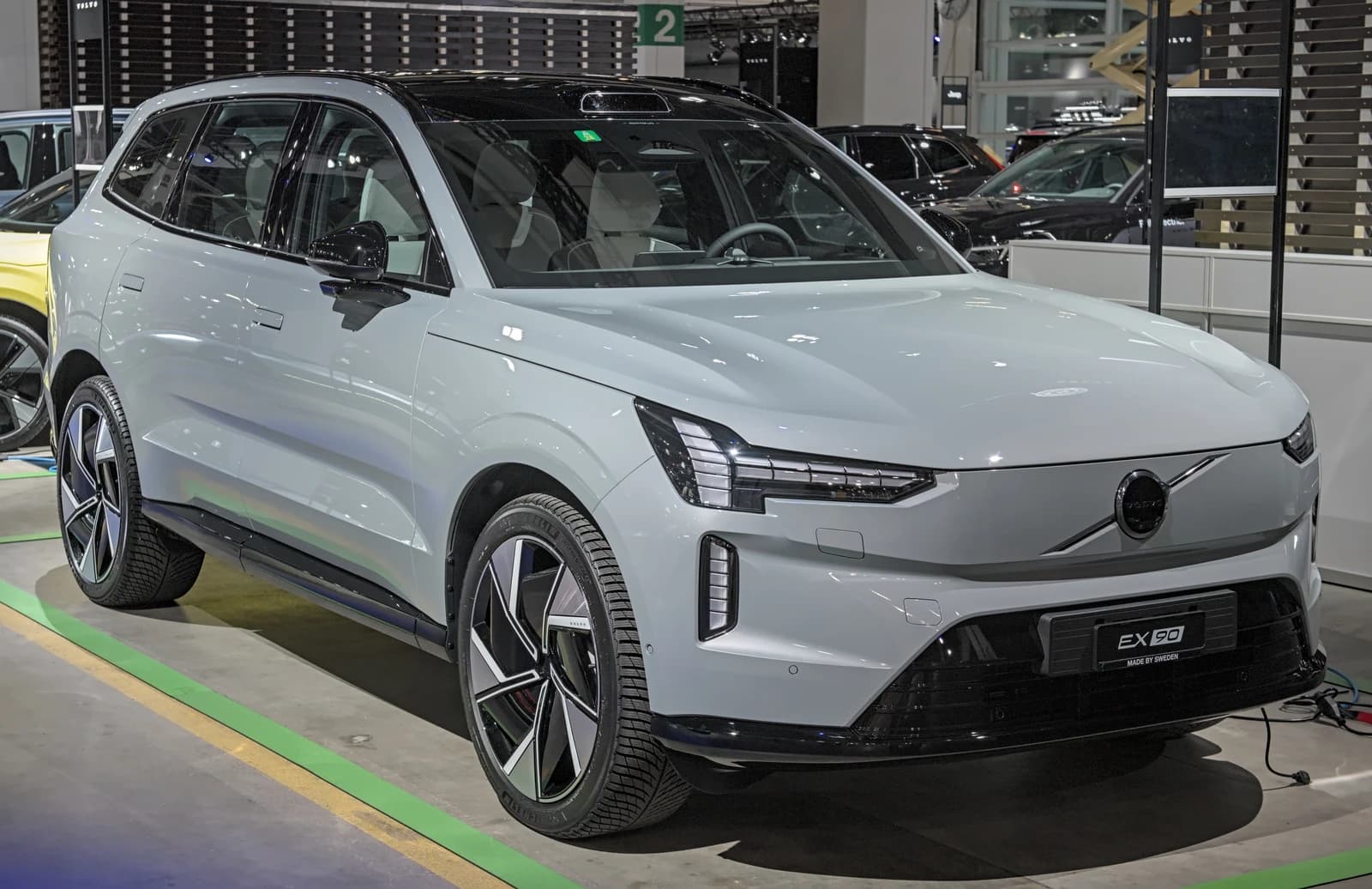 Light grey Volvo EX90 electric SUV on display at a car exhibition.