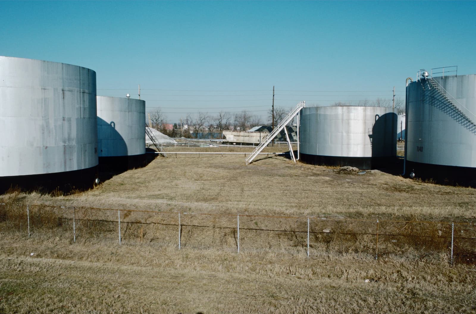Large cylindrical storage tanks for oil or other petrochemicals under a clear sky.