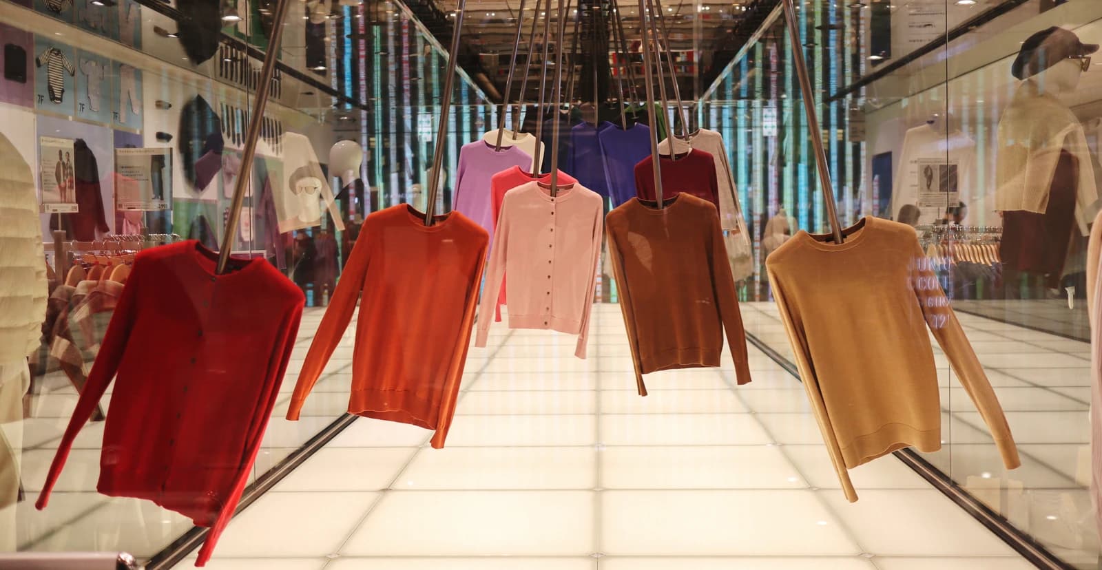 Sweaters in various colors displayed in the window of a UNIQLO store.