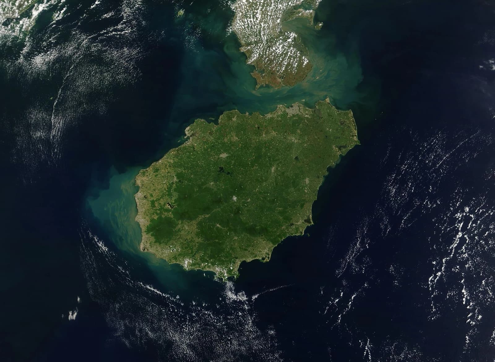 Satellite image shows Hainan Island, China, surrounded by dark blue ocean.