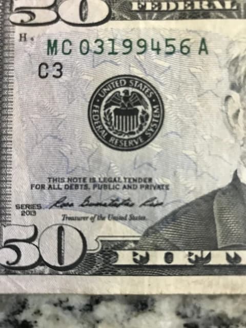 Close-up of a United States fifty-dollar bill featuring the Federal Reserve seal.