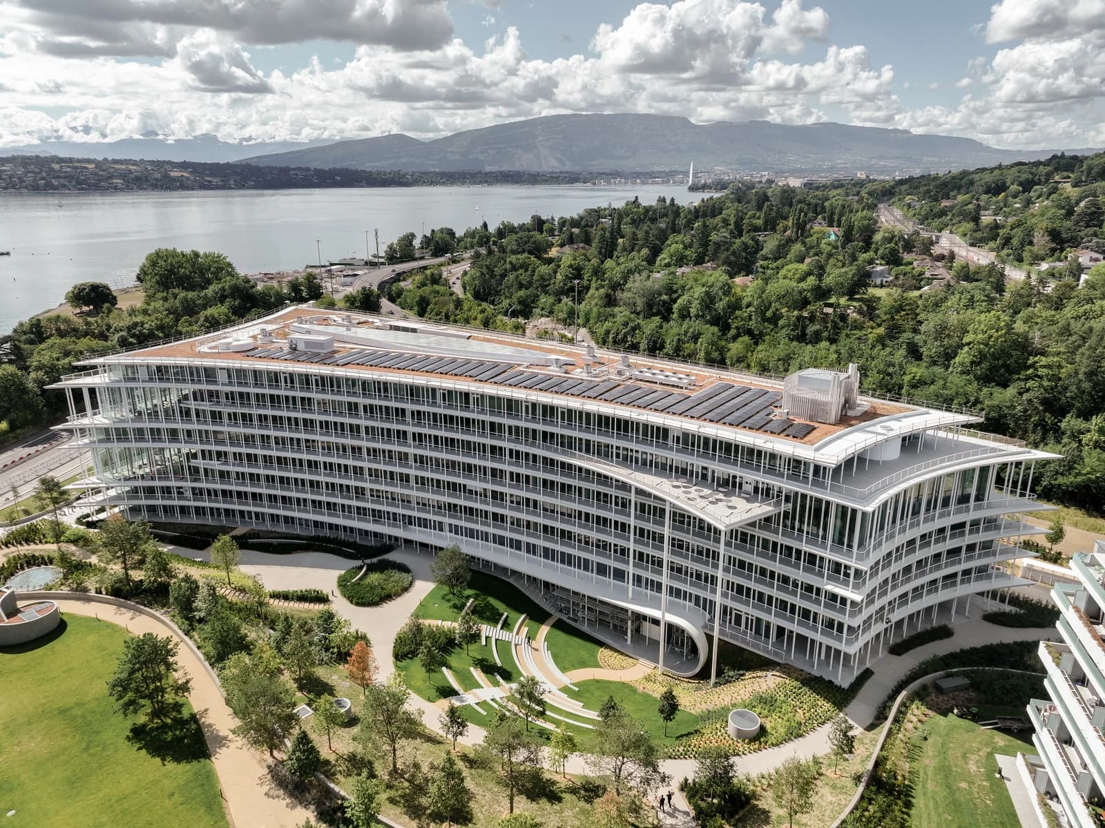Aerial view of Lombard Odier headquarters building with a lake and mountains in the background.