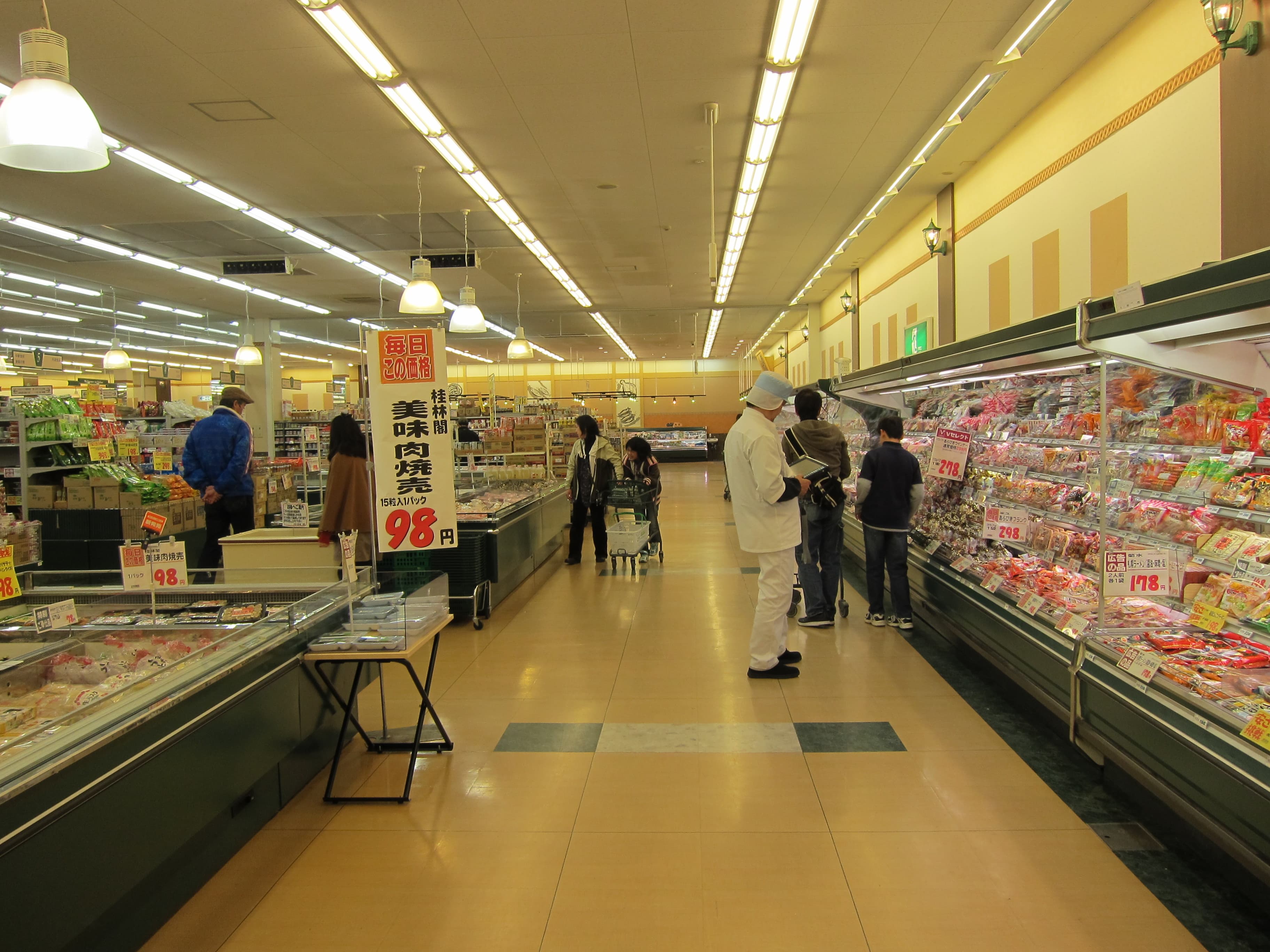 People shopping for groceries inside a brightly lit Japanese supermarket.