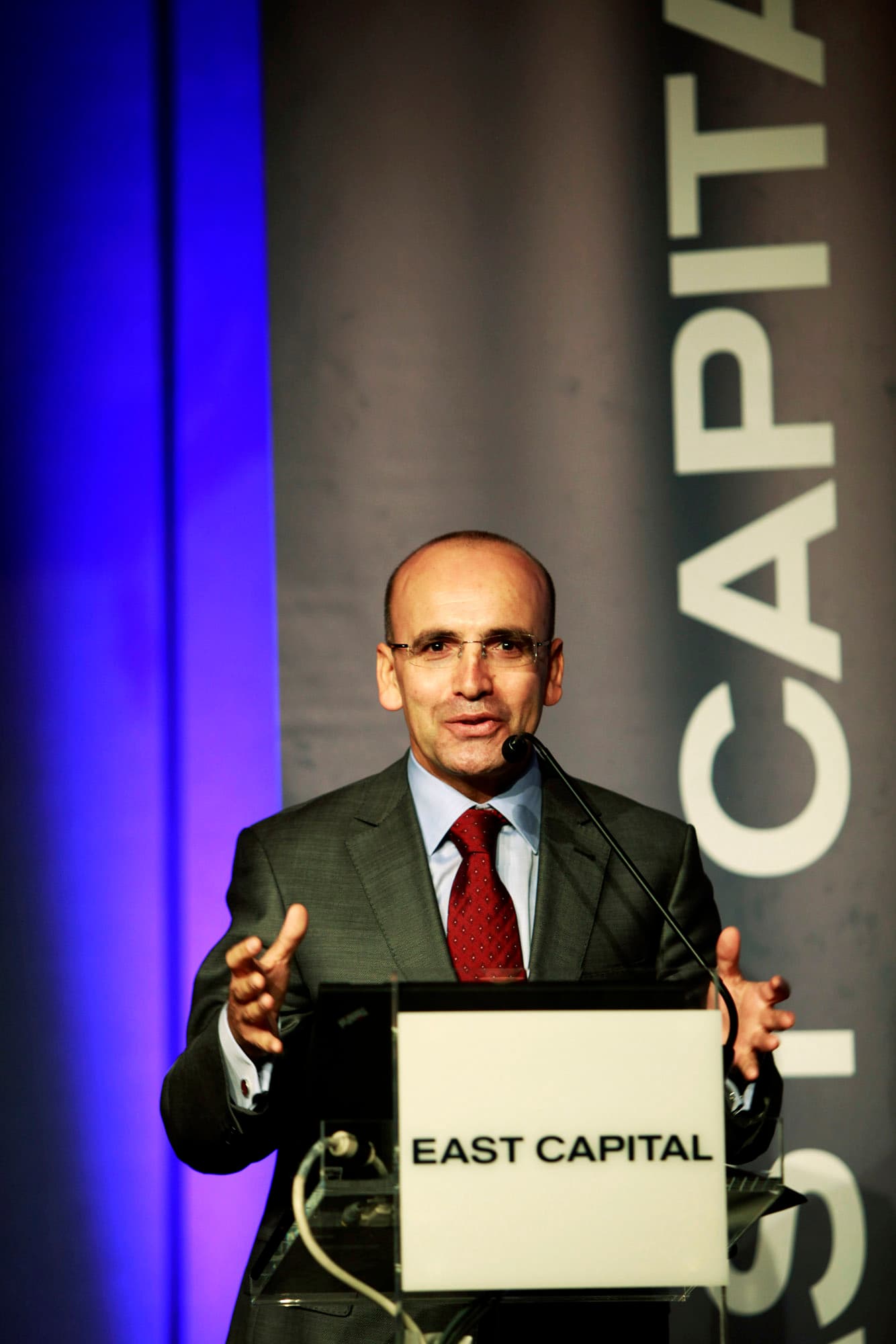 Mehmet Simsek, former Turkish Minister of Finance, speaking at a podium.