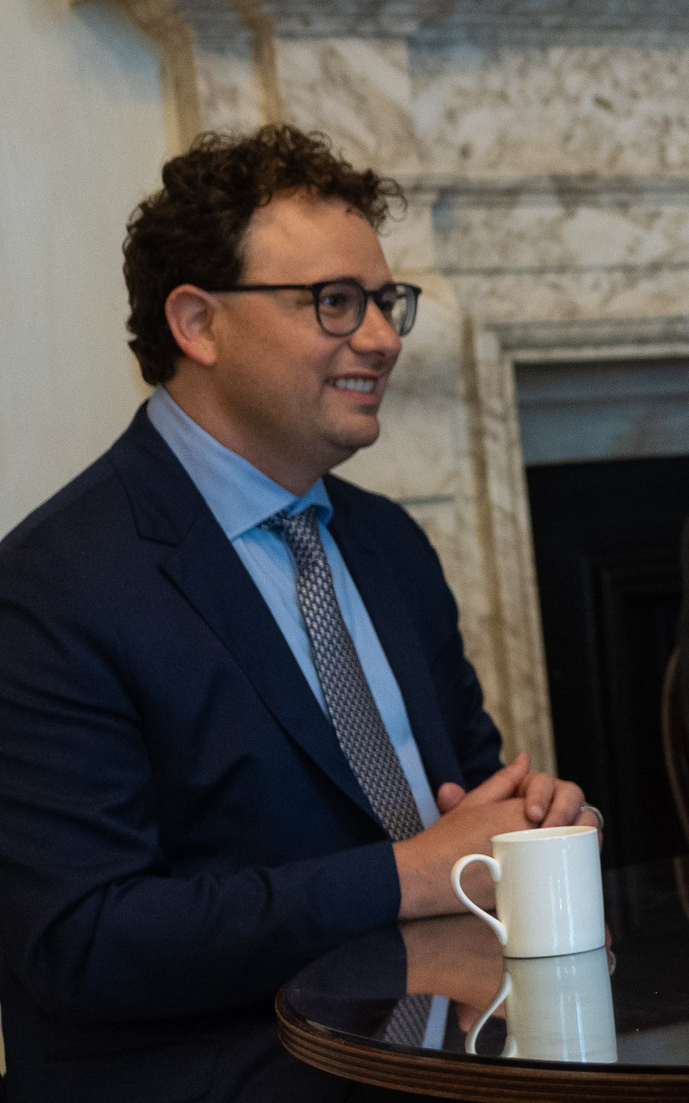 Dario Amodei, CEO of Anthropic, seated at a table with a coffee cup.