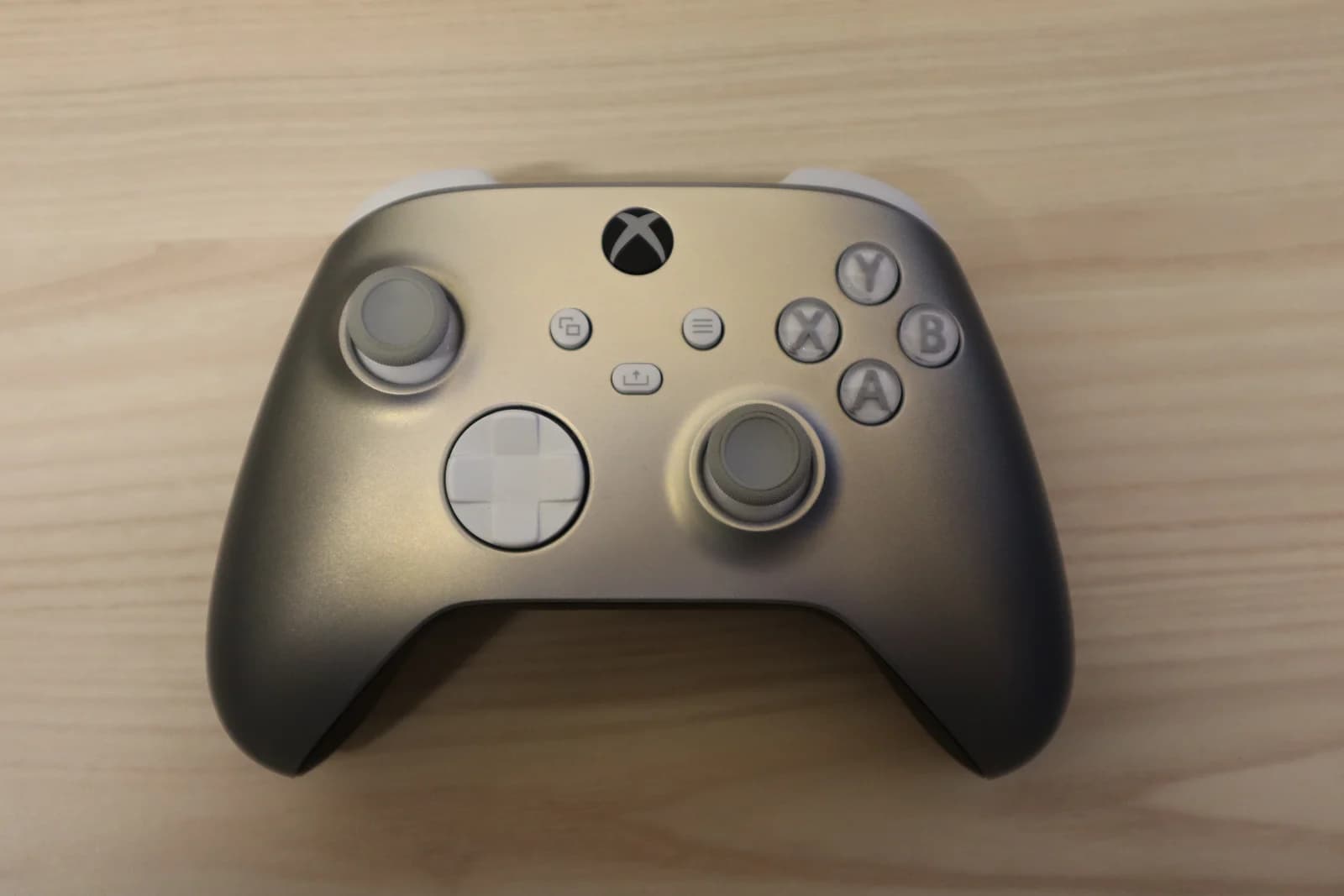 An Xbox Series Wireless Controller, Lunar Shift special edition, on a light wooden surface.