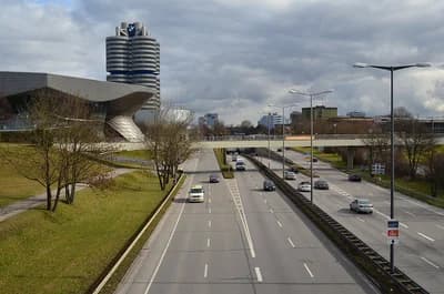BMW Headquarters and BMW Welt buildings in Munich, Germany, next to a multi-lane highway.
