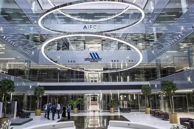 Interior of the Astana International Exchange building with people standing on the ground floor.