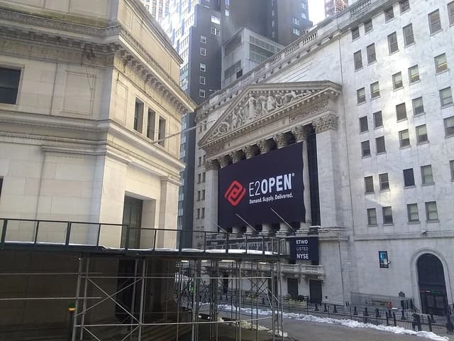 Exterior of the New York Stock Exchange building with a large E2open banner.
