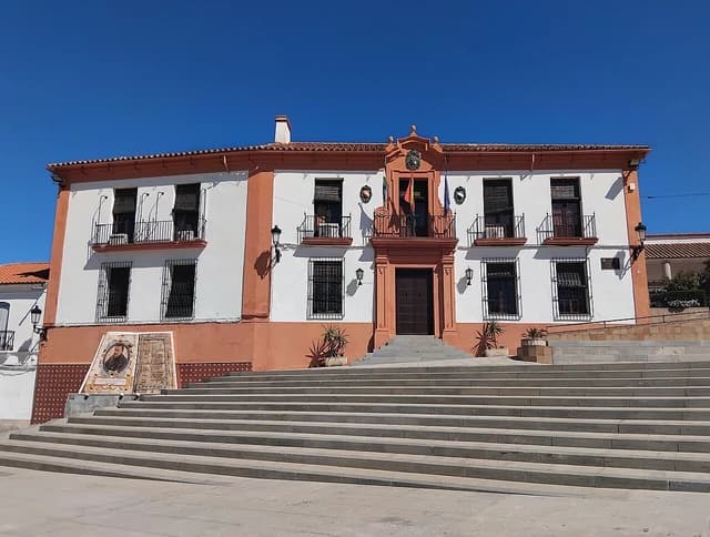 Casa Consistorial de Fuente Obejuna, a white and orange building with balconies and stairs.