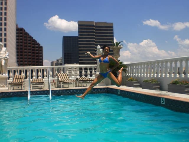 Woman jumping into a rooftop swimming pool at Le Pavillon Hotel, New Orleans.