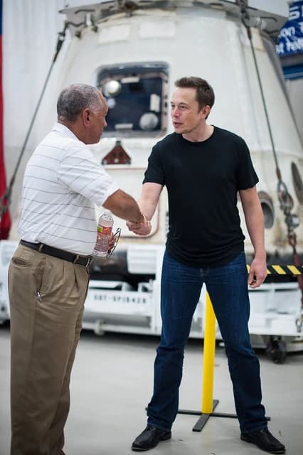 Charles Bolden, NASA administrator, shakes hands with Elon Musk, CEO of SpaceX, inside a facility.