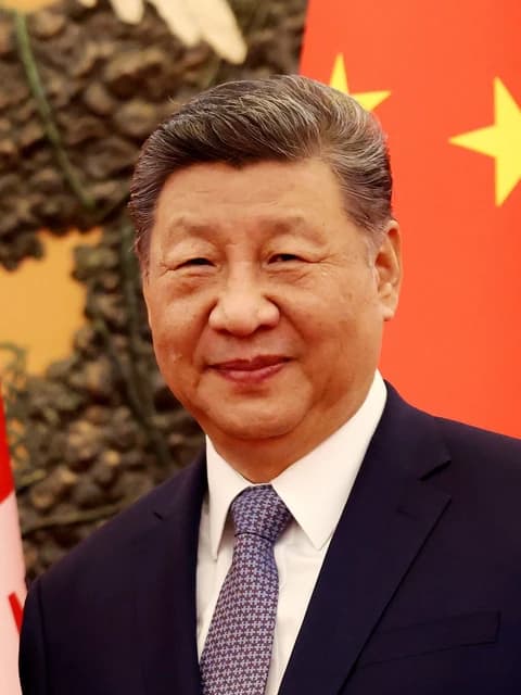 Xi Jinping, President of China, smiling while standing indoors.